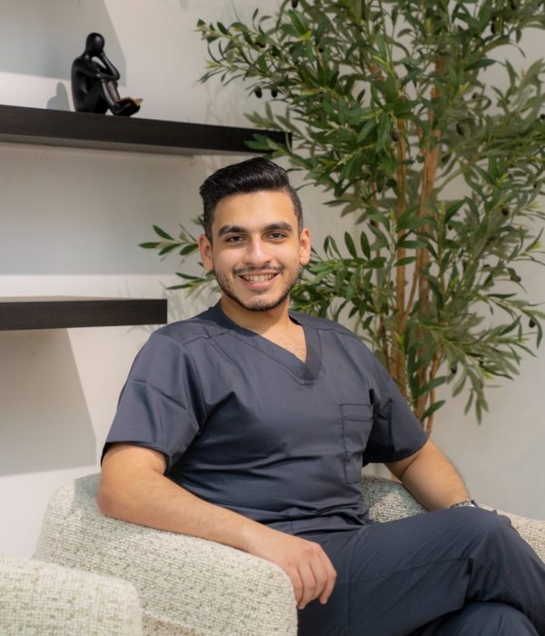 Dr. Mohamed Sharshera smiling confidently in a modern clinic setting, embodying the professional and welcoming atmosphere of a trusted dental clinic in Abu Dhabi, where patients receive exceptional care.