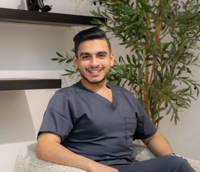 Dr. Mohamed Sharshera smiling confidently in a modern clinic setting, embodying the professional and welcoming atmosphere of a trusted dental clinic in Abu Dhabi, where patients receive exceptional care.